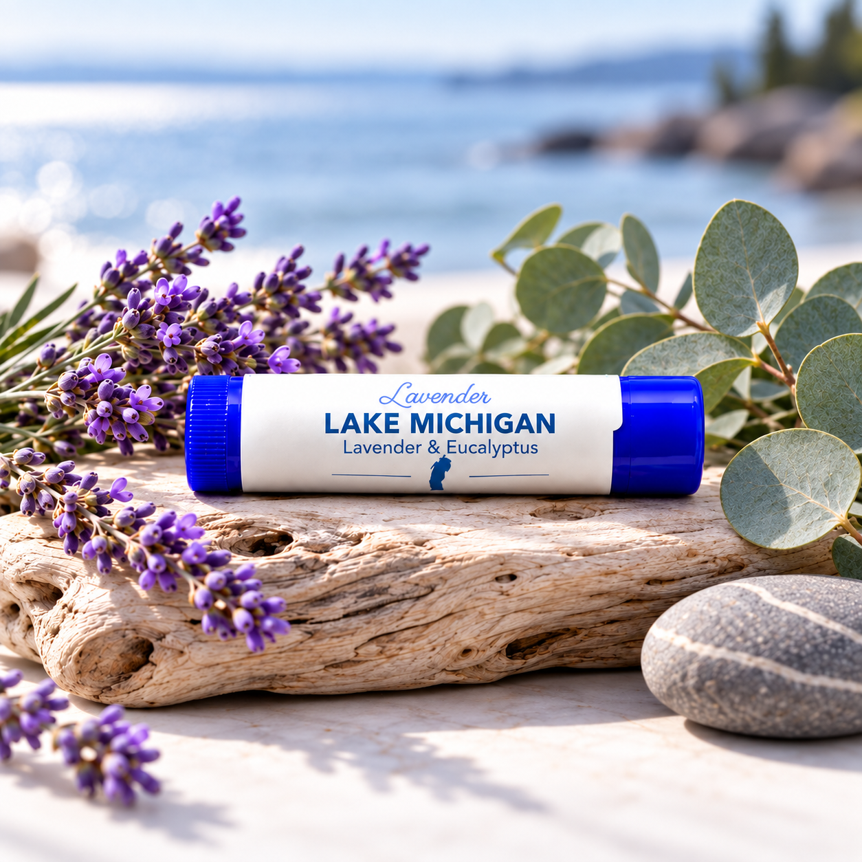 Lavender Lake Michigan Lip Balm tube on driftwood with lavender and eucalyptus by the water